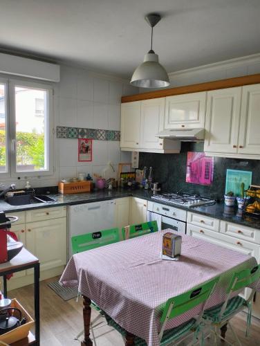 une cuisine avec une table recouverte d'une nappe dans l'établissement Maison au calme wifi Netflix, à Hendaye