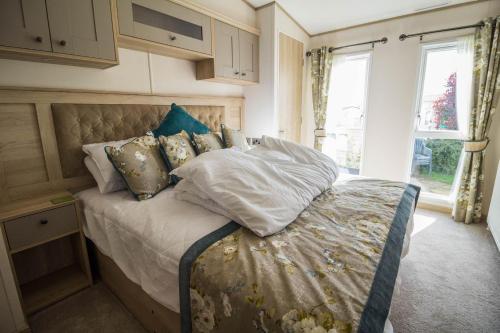 Un dormitorio con una cama con almohadas. en Beautiful Lodge At Manor Park In Hunstanton Ref 23018k en Hunstanton