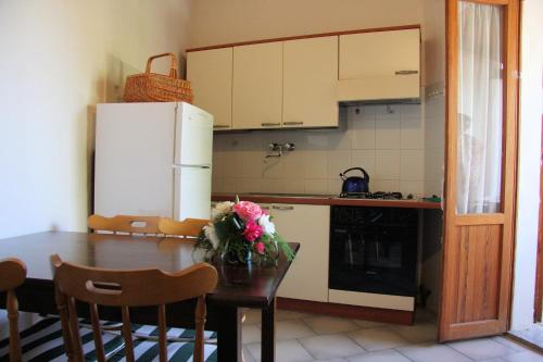 a kitchen with a table and a white refrigerator at Sa Fiorida case vacanze in Valledoria
