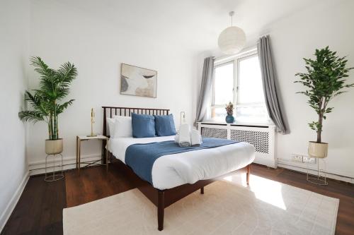 倫敦的住宿－3BDR Kings X Apt for 7 with Balcony and near tube，一间卧室配有一张带蓝色枕头的床和一扇窗户。