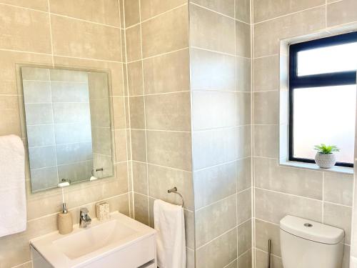 a bathroom with a sink and a toilet and a mirror at Ballito Hills - Ocean View, Queen Bed & Free Wi-Fi in Durban