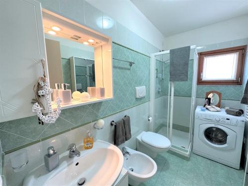 a bathroom with a sink and a washing machine at Porto Antico Village in Aprilia Marittima