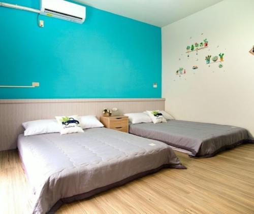 Duas camas num quarto com uma parede azul em 上海民宿 em Chaozhou