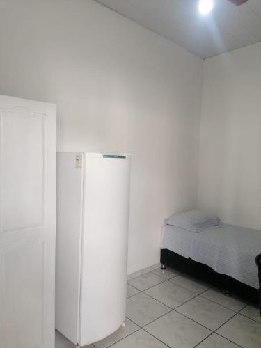 um frigorífico branco num quarto com uma cama em Quarto para Rapazes no Centro Sinop MT em Sinop