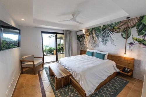 a bedroom with a large bed and a large window at Marala Hotel in Esterillos