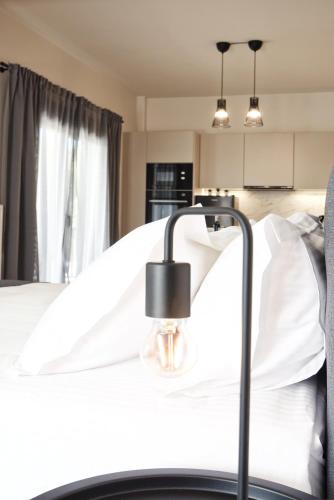 a bed with white sheets and a lamp on it at Aellō luxury apartments in Markopoulo