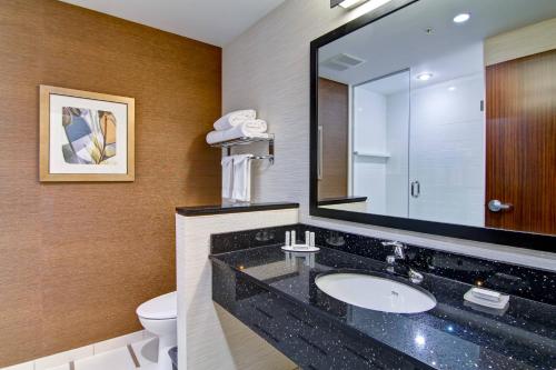 a bathroom with a sink and a mirror and a toilet at Fairfield Inn & Suites by Marriott Kamloops in Kamloops