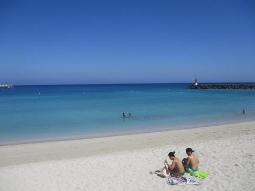 a group of people sitting on the beach at Casa Azul Montecastillo L7 in Caleta De Fuste