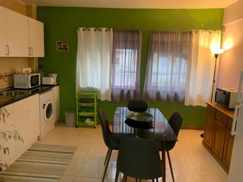 uma cozinha com uma mesa e uma sala de jantar com paredes verdes em Charming T1 apartment in Seixal em Aldeia de Paio Pires