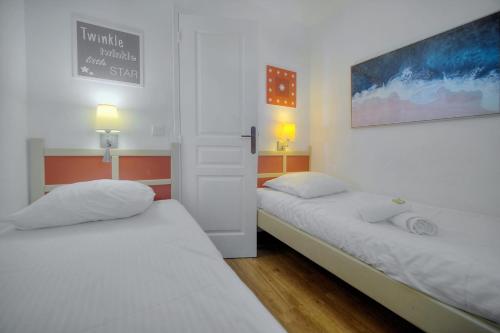 deux lits dans une petite pièce aux murs blancs dans l'établissement IMMOGROOM - sea view - Pool - Terrace - Parking - Wifi - AC, à Cannes