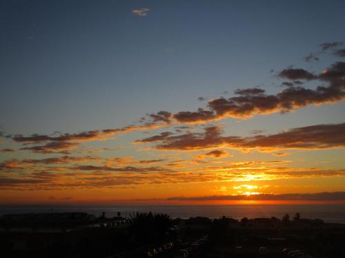 a sunset with the sun setting over the ocean at Casa Ayla Montecastillo A8 in Caleta De Fuste