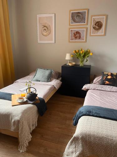 a bedroom with two beds and a table with a vase at Apartament Leszczyna in Olsztyn