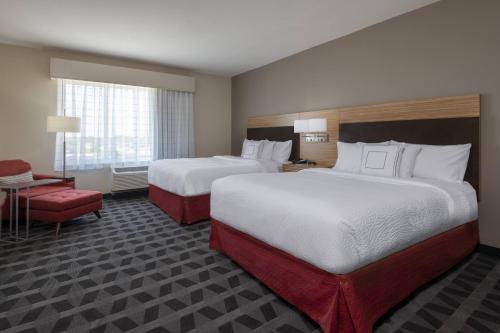 a hotel room with two beds and a chair at TownePlace Suites by Marriott St. Louis Edwardsville, IL in Edwardsville