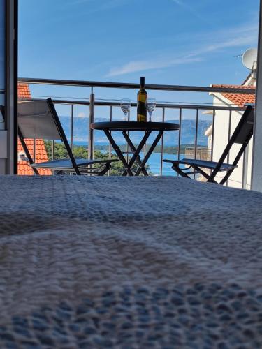 a table with a bottle of wine on a balcony at Jelsa Blue Sea View in Jelsa