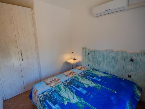 a bedroom with a bed with a blue comforter at Appartamento Santa Maria Porto Pollo in Palau