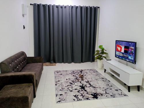 Afna Home stay في كوالا ليبيس: غرفة معيشة مع أريكة وتلفزيون
