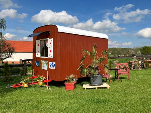 a red shed with a table and potted plants at Schäferwagen Kuschel vom Friesenhof Wieratal in Nobitz