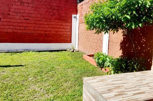een tuin met een rode bakstenen muur en een witte deur bij "Village" Amplia CASA boutique con parrilla y 2 garages in Corrientes