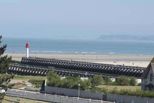 a bridge over a beach with a red lighthouse at Les Embruns - Plein ciel - appartement 3eme étage in Deauville
