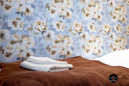 uma cama com toalhas com papel de parede floral em CukroVia em Kutno