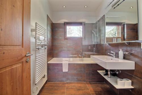 ein Badezimmer mit einem Waschbecken, einer Badewanne und einem Spiegel in der Unterkunft 150 Sqm Apartment 4 Min Walk Cable Car in Champéry