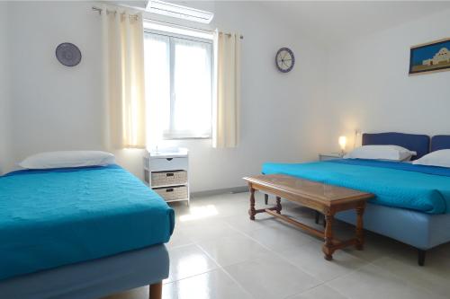 a bedroom with two beds and a table in it at Maison Marie in Cala Gonone