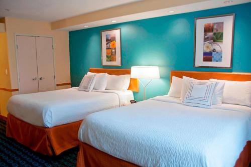 two beds in a hotel room with blue walls at Fairfield Inn & Suites Ames in Ames