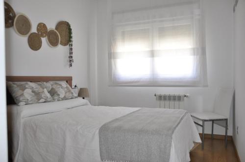 a white bedroom with a bed and a window at Alojamiento Santa Maria Bertamirans in Ortoño