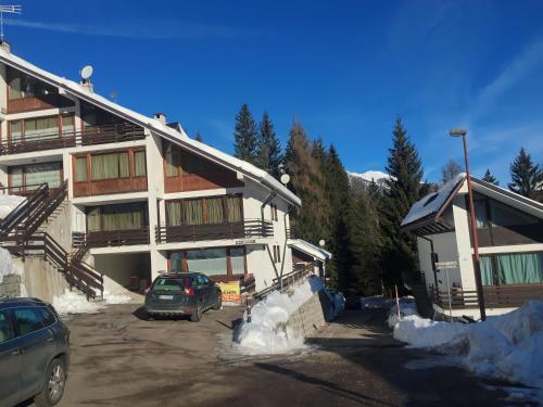 a large building with cars parked in a parking lot at Casetta dei Cuori - Alpine Style Cozy Apartment in Folgarida