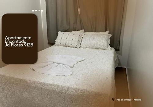 een bed met witte lakens en kussens in een kamer bij APARTAMENTO ENCANTADO JD FLORES 912 - 1º andar in Foz do Iguaçu