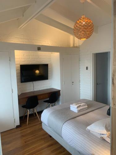 Un dormitorio con una cama, un escritorio y un televisor. en Laura del Mar Hotel Boutique, en Concón
