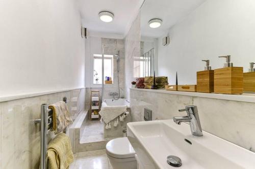 Baño blanco con lavabo y aseo en Modern one bedroom in Fitzrovia, Central London, en Londres