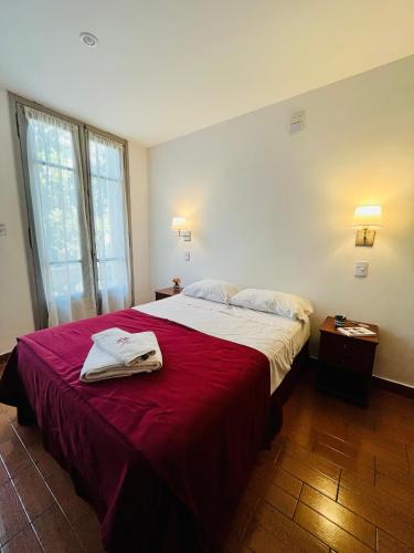 a bedroom with a large bed with a red blanket at Hotel Alcazar in Buenos Aires