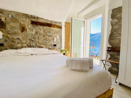 a white bed in a room with a stone wall at Casa Caterina in Lezzeno