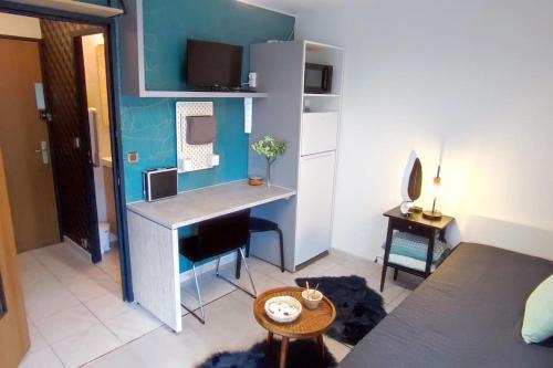 Cette petite chambre comprend un bureau et une table. dans l'établissement MICHELET Studio climatisé avec balcon et parking ferme, à Montpellier