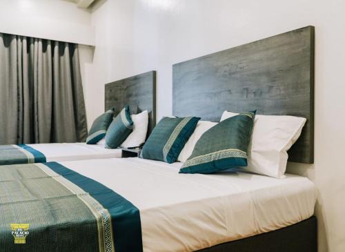 two beds in a bedroom with blue and white pillows at El Palacio Hotel & Resort in Cavite