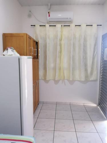 a kitchen with a refrigerator and a curtain at quarto para Rapaz, centro, Sinop MT in Sinop