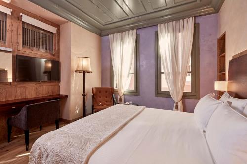a bedroom with a bed and a desk and a television at Domus Renier Boutique Hotel in Chania Town