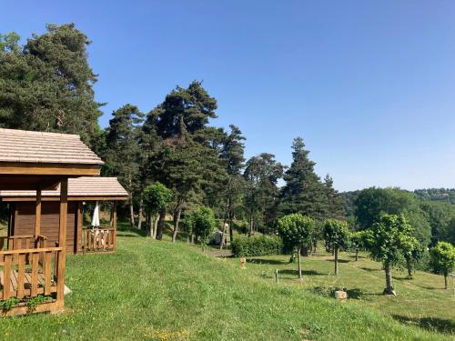 a cabin in a field with trees in the background at Camping Sérendipité in Neuvéglise