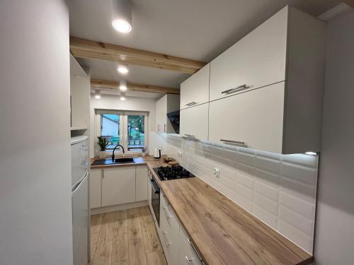 a kitchen with white cabinets and a wooden floor at Domek góralski in Borki