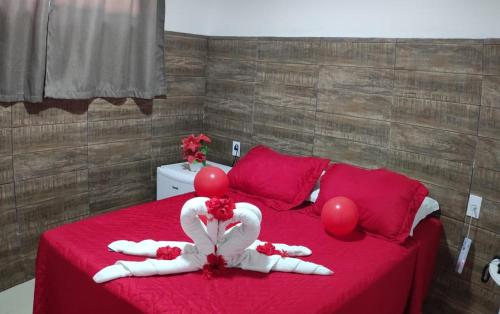Un dormitorio con una cama roja con globos rojos. en Cabanos Suites, en Maragogi