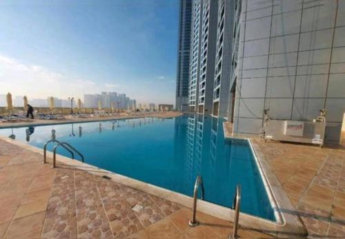 Luxury full sea view flat في عجمان: مسبح كبير بجانب مبنى طويل