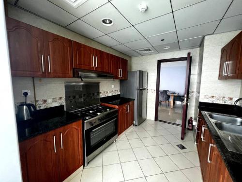 a kitchen with wooden cabinets and a stove top oven at Luxury full sea view flat in Ajman 