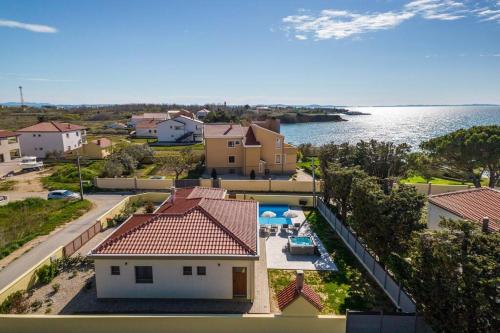 an aerial view of a house and the water at Villa Mattina, with heated pool and jacuzzi in Privlaka