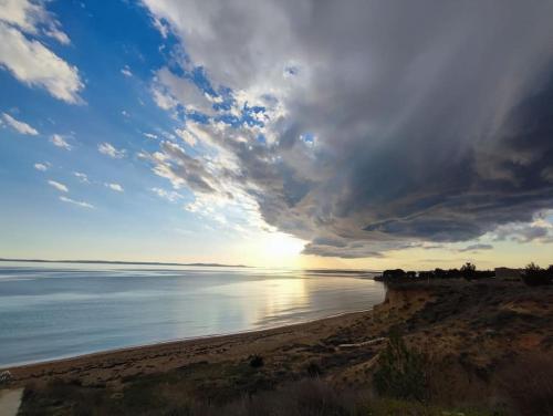 a beach with a cloudy sky and the ocean at Villa Mattina, with heated pool and jacuzzi in Privlaka