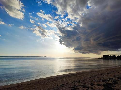 a beach with a cloudy sky and the ocean at Villa Mattina, with heated pool and jacuzzi in Privlaka