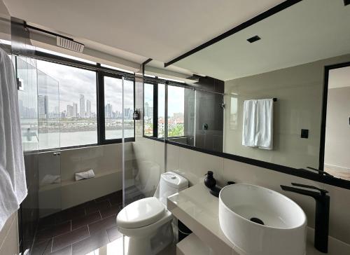 uma casa de banho com um lavatório, um WC e uma janela. em AmazINN Places Penthouse Deluxe, Skyline and Private Rooftop na Cidade do Panamá