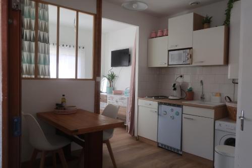 uma cozinha com armários brancos e uma mesa de madeira em Coté Lac mini em Mimizan