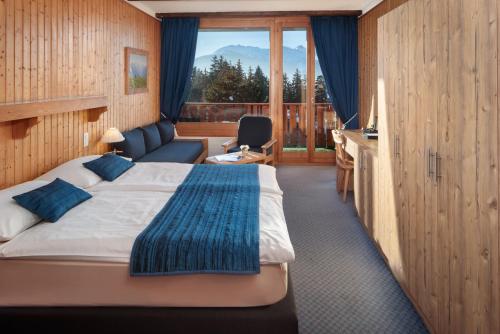 Habitación de hotel con cama, escritorio y ventana en Hotel La Prairie, en Crans-Montana