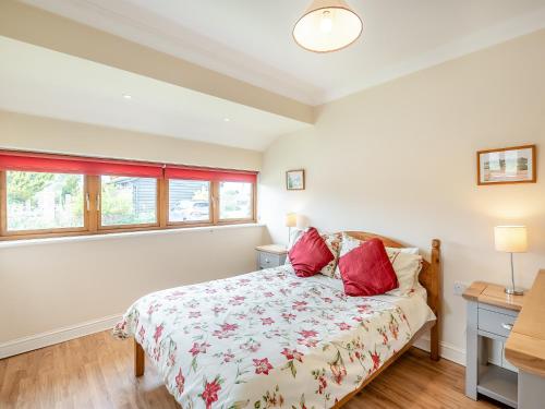 a bedroom with a bed with red pillows on it at Orchard Cottage in Saint Osyth